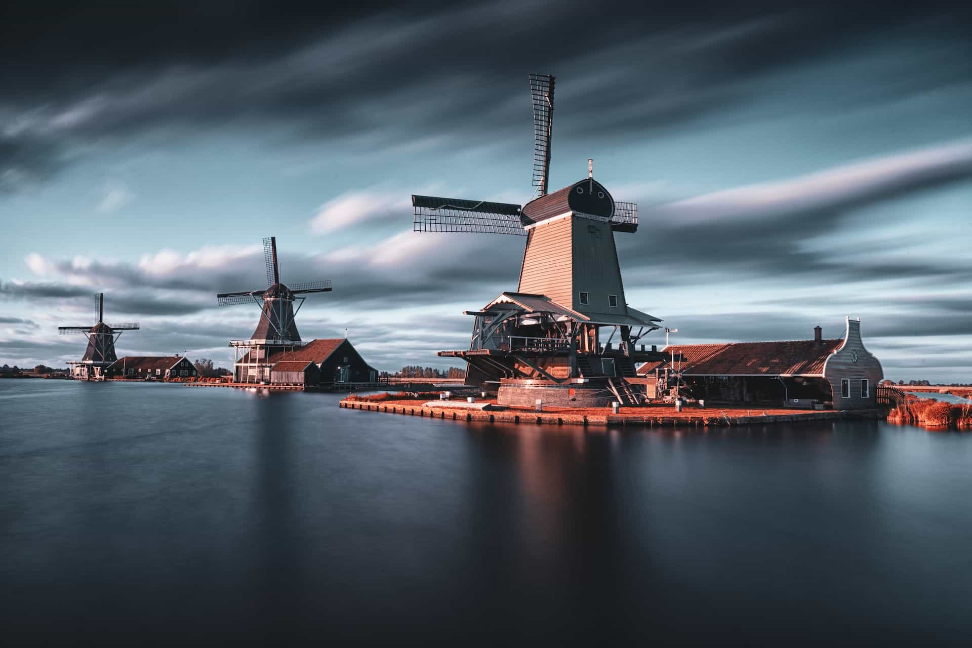 Three windmills by the water in the Netherlands.