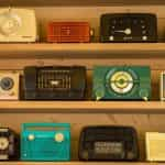 Rows of colorful retro radios sit on wood shelves.