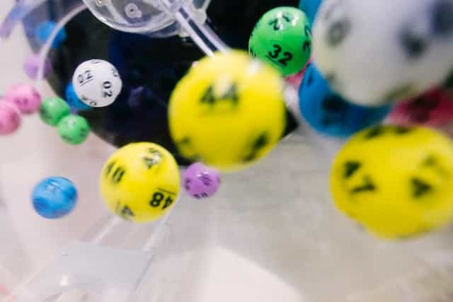 Multi-colored lottery balls fly around a barrel.